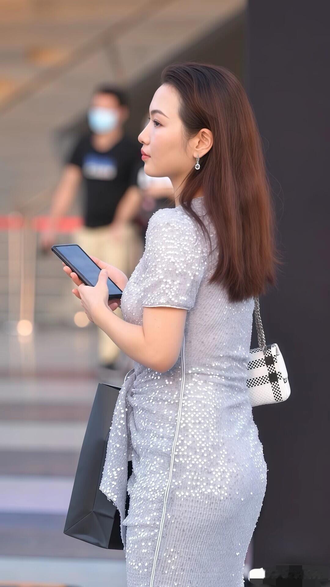 时尚都市女郎，手拿购物袋，漫步在繁华街头。