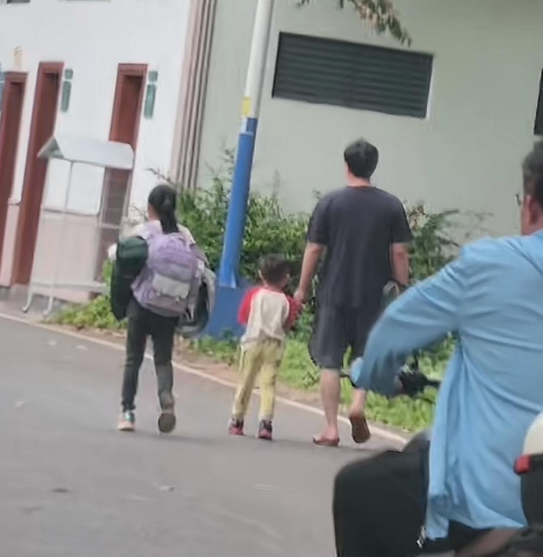 五一出游期间，网友记录下来扎心的一幕，爸爸带着两个孩子去公园露营的路上。女儿手里