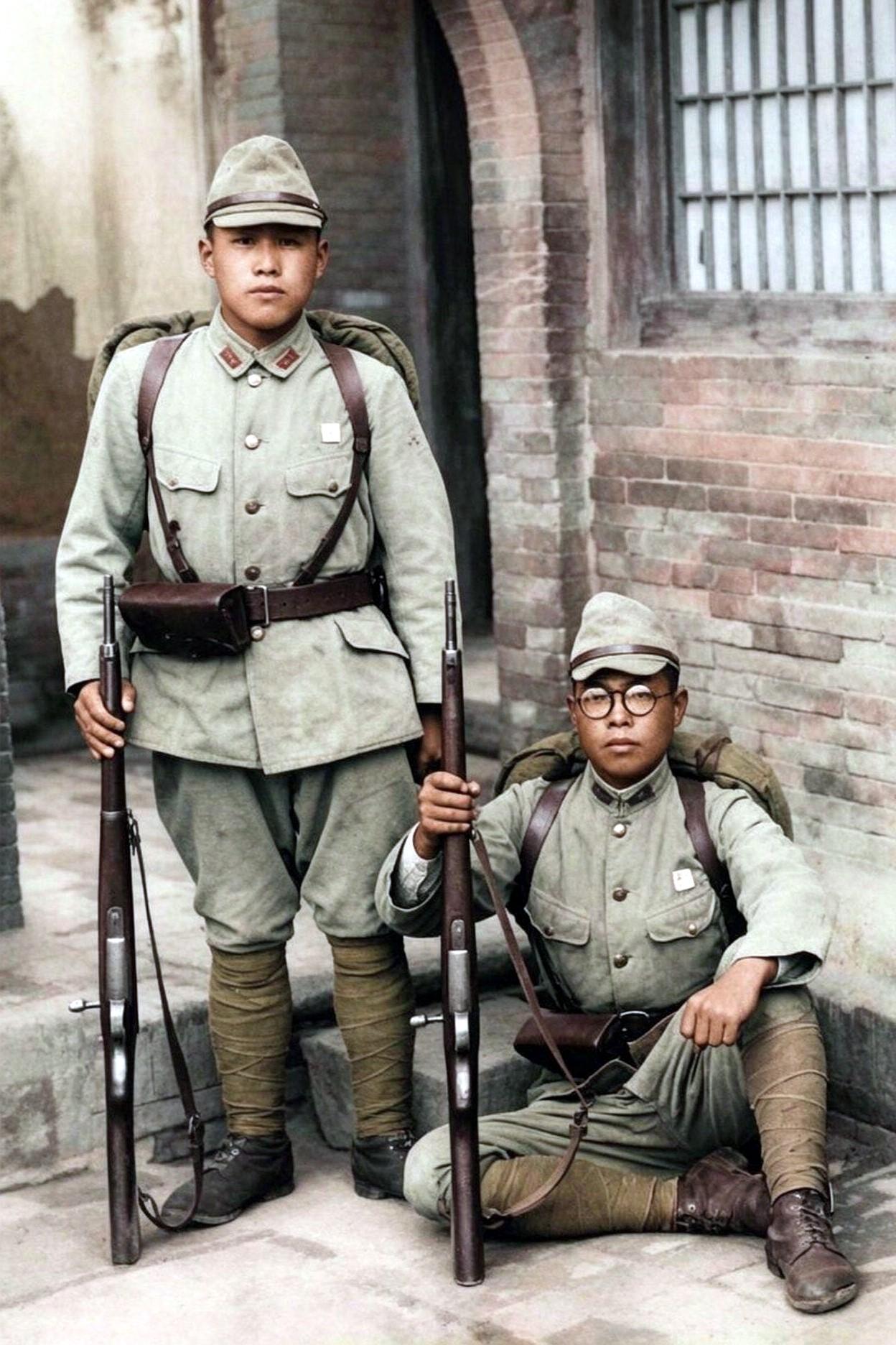 日本侵华时期，鬼子兵在河南新乡拍摄的一张照片。画面中，两头鬼子一坐一站，手里攥着