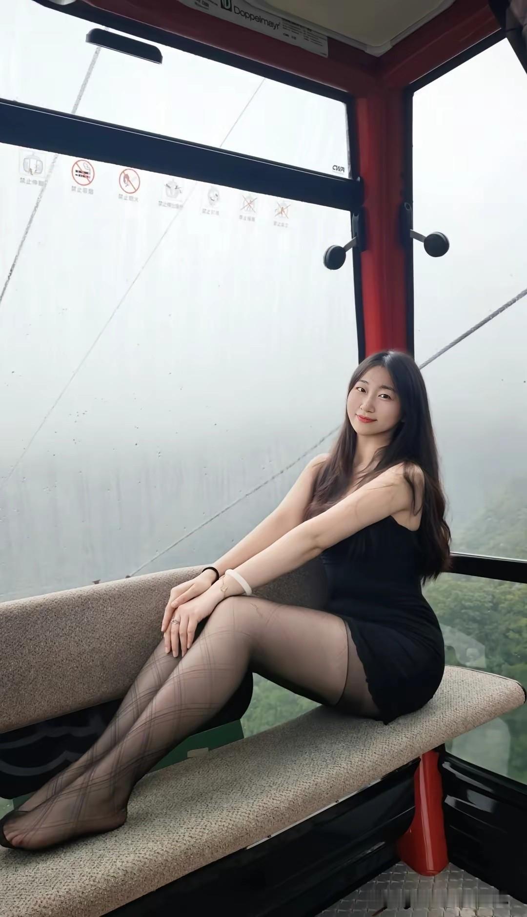 她坐在缆车里，微笑着看向镜头。拍美女好看
