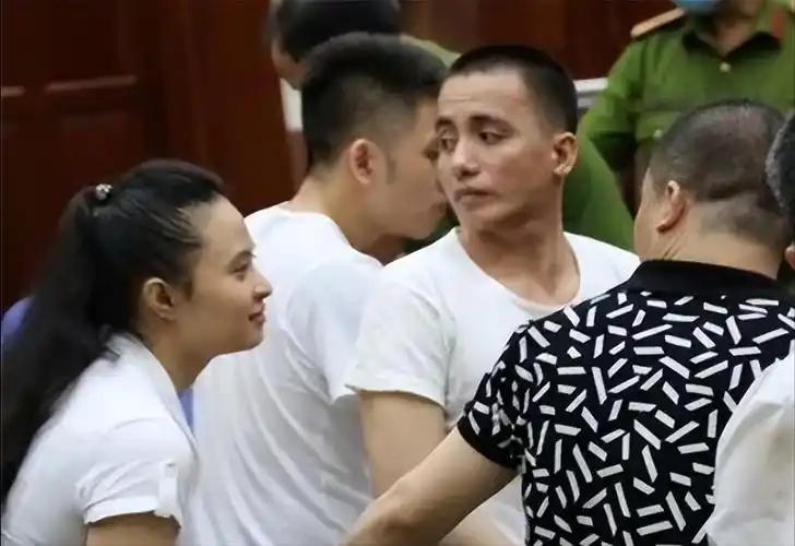 2021年越南，戴着手铐的大毒枭文敬阳，当着法官、法警和一堆记者的面，扭头朝着身