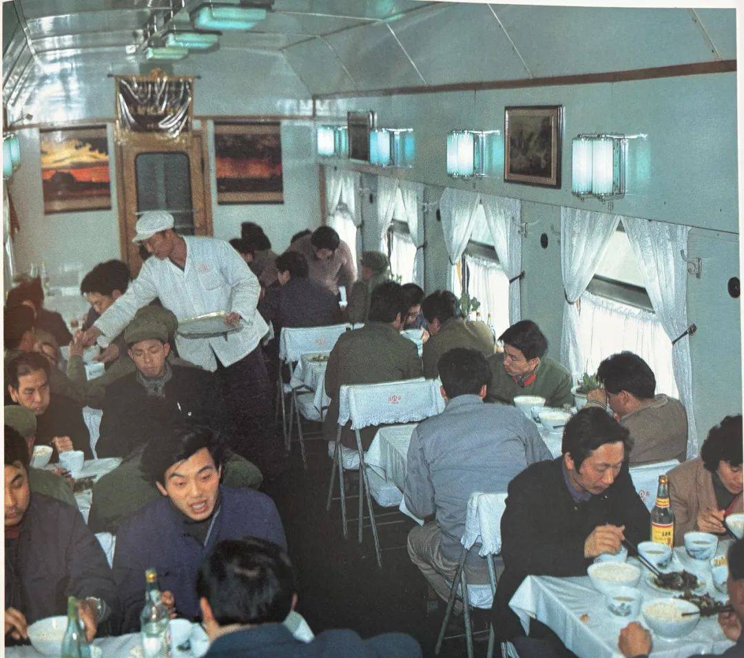 这张照片呈现的是列车餐车内部的场景。餐车整体环境清爽，桌椅摆放整齐，几乎满座，旅