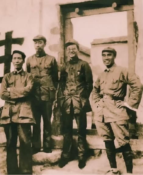 一张黑白照片，四个人站在一起，个个颧骨突出，脸颊凹陷，衣服松松垮垮地挂在身上，像