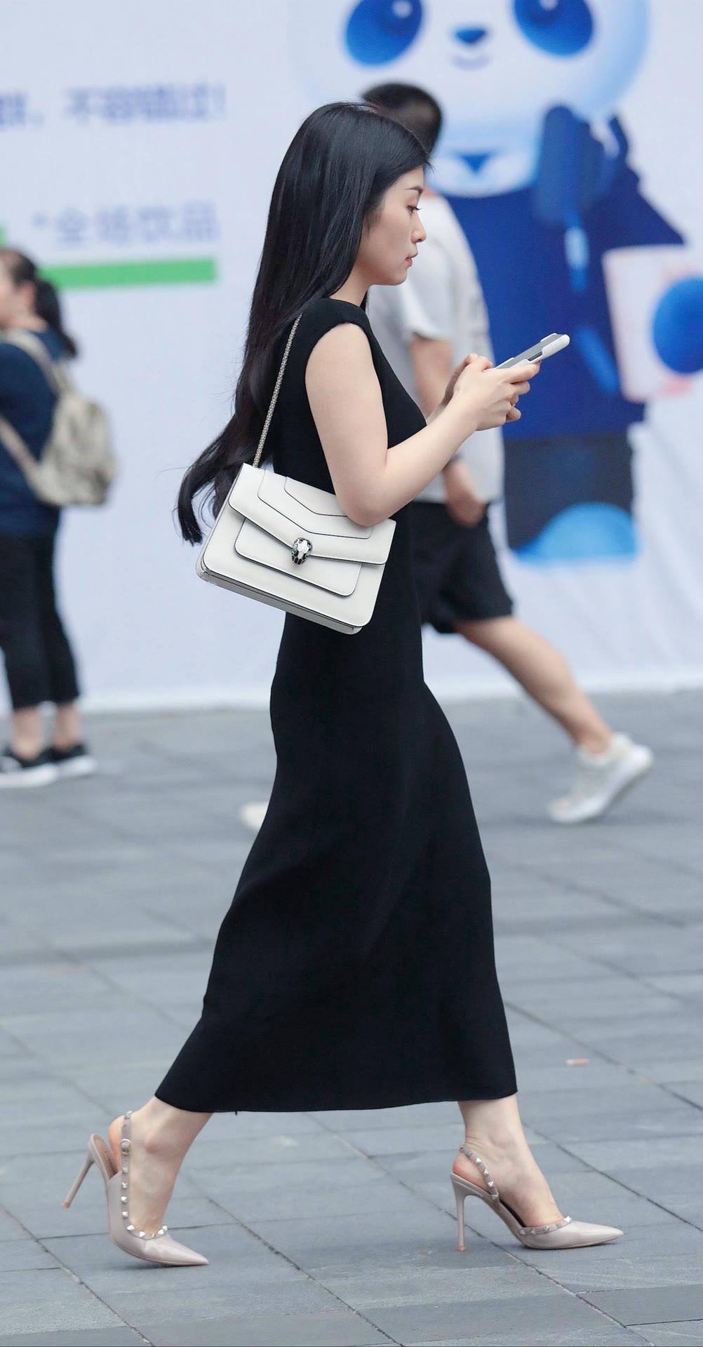 纯黑色长款连衣裙配搭一只米白色单肩包，简约而不失优雅。