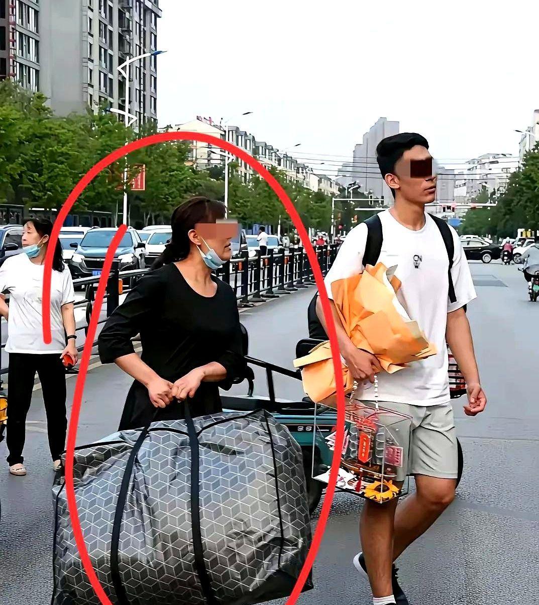 高考完的母亲接儿子回家，高大威猛的儿子一手鲜花一手小礼品走得悠哉，身旁不年轻的母
