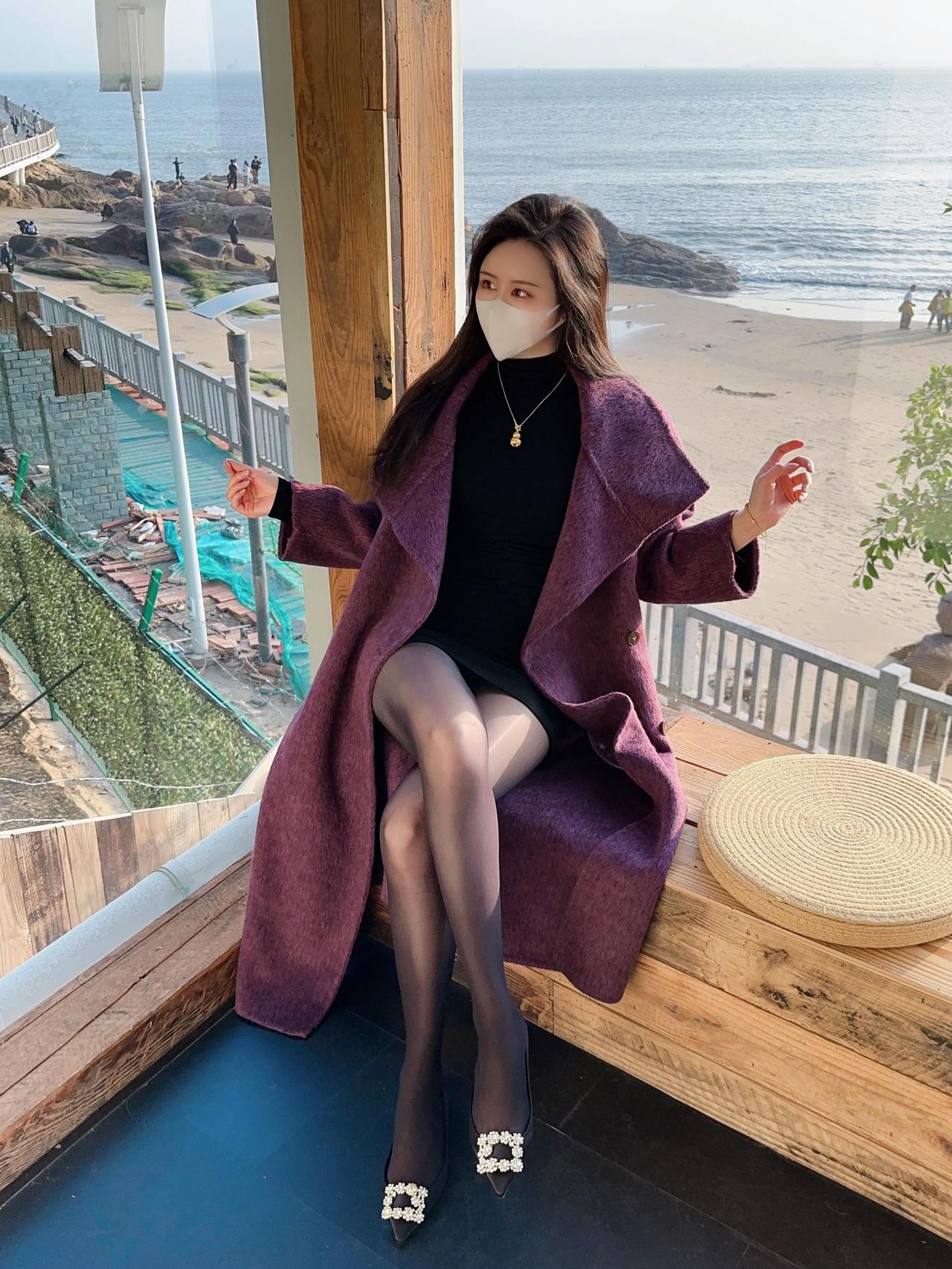 女人如何穿高跟鞋显得很洋气海边的风裹着暖意，紫色大衣藏住冬日余温，黑丝与钻扣鞋是