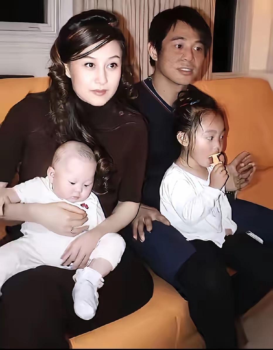 这是李连杰与妻子利智，以及两个女儿的家庭旧照，利智怀里的婴儿是李苔蜜，旁边吃东西