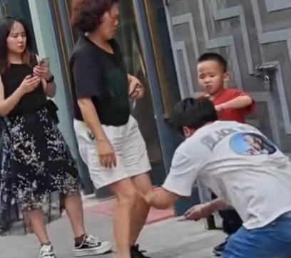 街头，一男子跪在水泥地上，向劈腿老婆连磕三个响头，哭喊：“我一天打两份工，从早