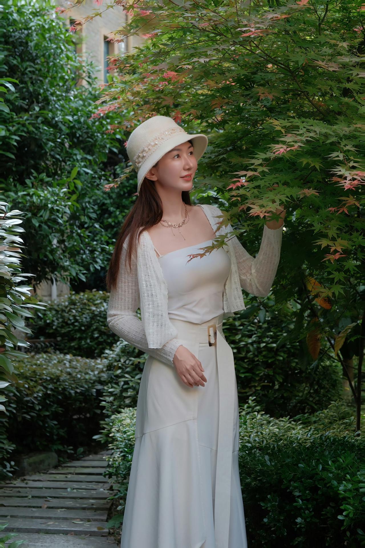 一袭白裙，一顶软帽，在绿意与光影里，赴一场温柔的午后之约。风穿过枝叶，带着初