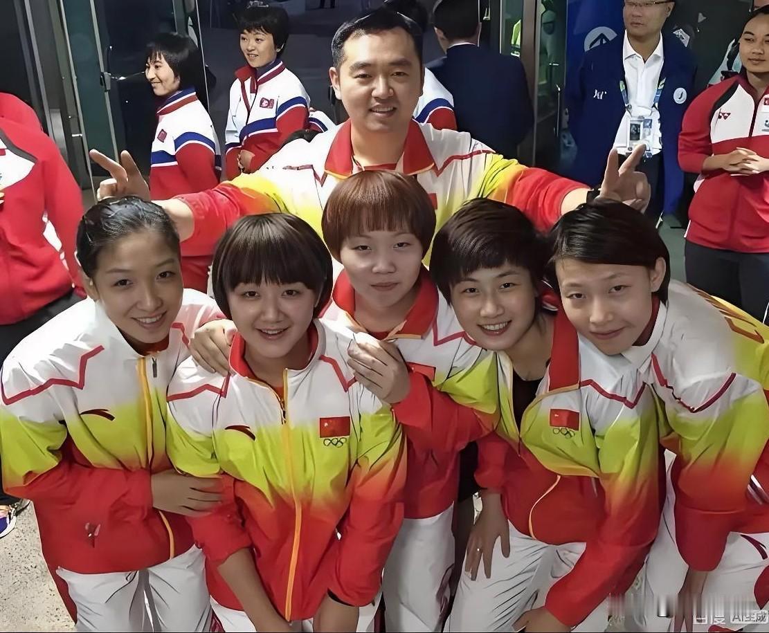 孔令辉展臂而立，如同保护幼雏的母鸡。身前丁宁、刘诗雯、陈梦、朱雨玲一众女将，小荷