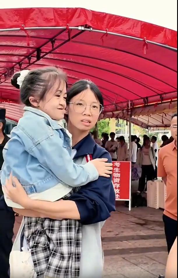 1女生走出考场后，没有四处找陪考的妈妈，反而蹲下身子，抱起一个“小女孩”，再仔细