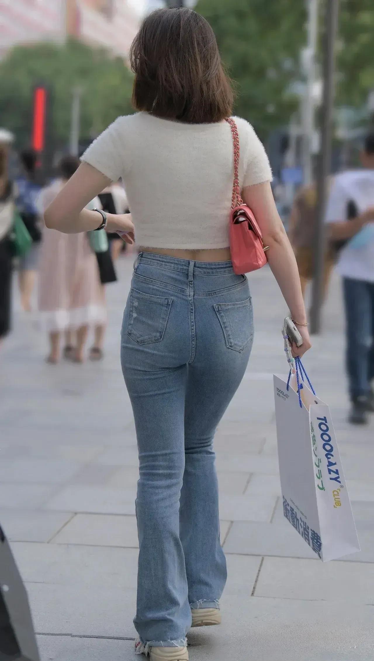 街拍一个紧身牛仔裤女孩在街上闲逛。紧身牛仔裤秀紧身裤女神背影紧身裤美女时尚