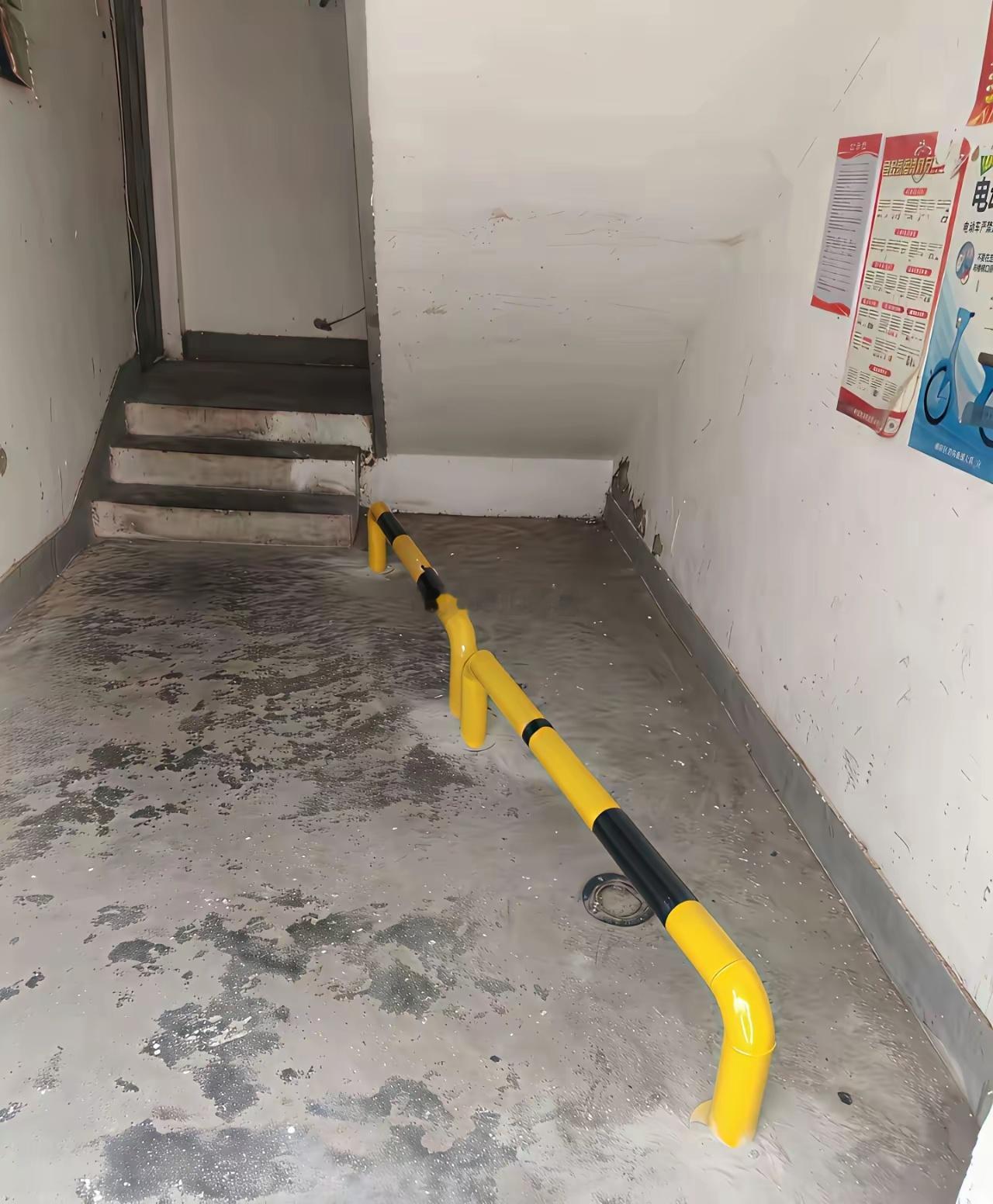 一位网友在自家小区楼下拍到的，楼梯底下突然被物业安装了两个横杠，但我实在搞不懂，