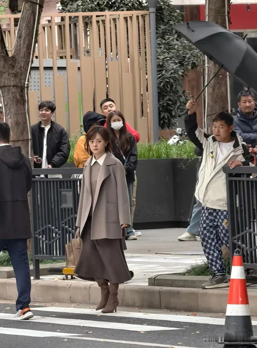 孙俪在无锡拍戏，一头棕色俏皮的短卷发，身穿灰色呢大衣和半身裙，脚踩靴子，肤色很白
