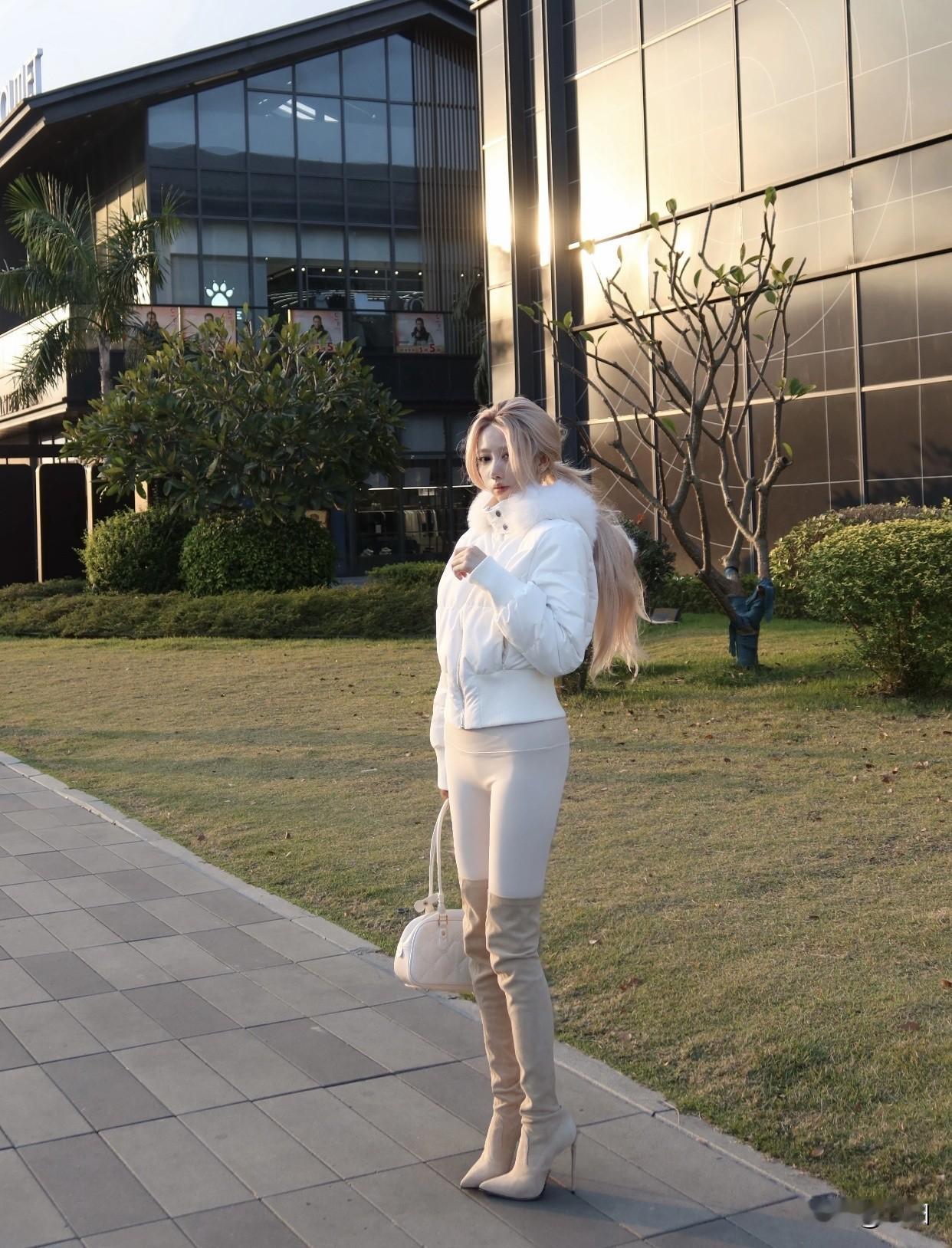 冬日暖阳下，优雅白衣搭配高筒靴，尽显都市女性魅力。