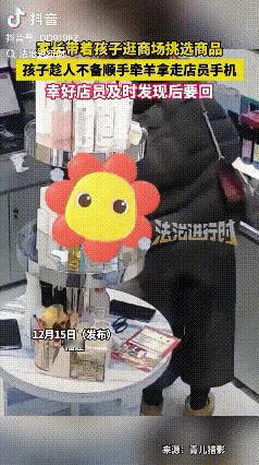 母亲带着个七八岁的孩子在一商店挑选商品，孩子趁着店员不注意时拿走了放在柜台上的手
