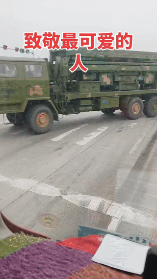 几辆军车通过一个十字路口。几个战士站在路口临时进行交通管制。虽然会耽误一点时