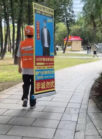 雇主下单跑腿任务，拜托外卖小哥扛着相亲立牌沿路送去相亲角。小哥接单后老老实实背