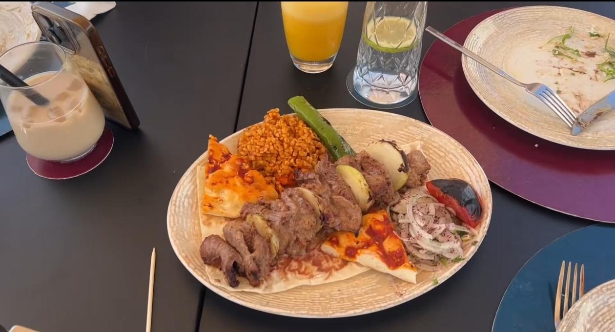 烤肉搭配粗粮饭与薄饼，烤青椒、腌洋葱点缀其间，满满土耳其风味。冰奶茶与鲜榨橙汁摆