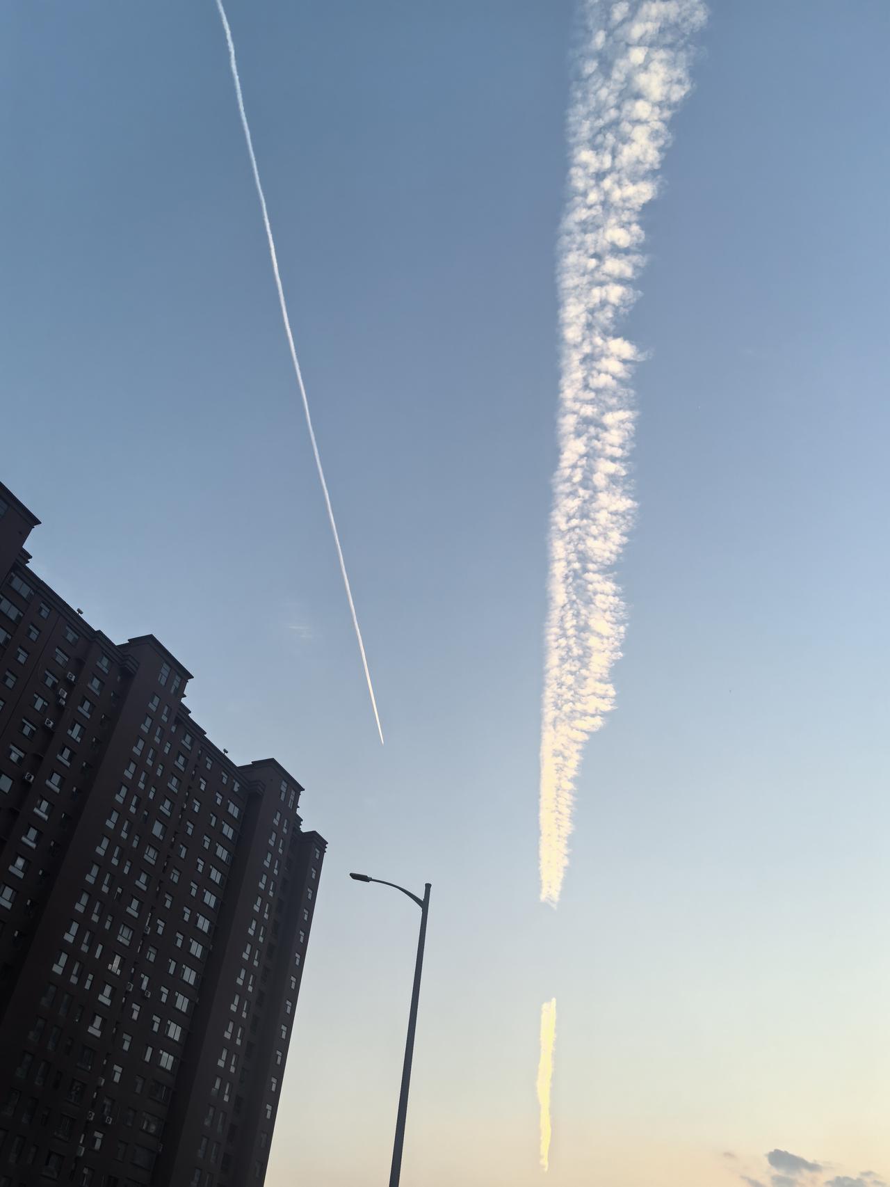 城市上空飞机留下长长的云迹，是不是很有趣啊？