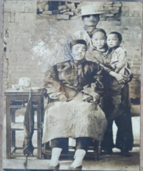 🌞她用手撑着丈夫的遗体，拍下了这张“全家福”，那男人戴着瓜皮帽，穿着马褂，