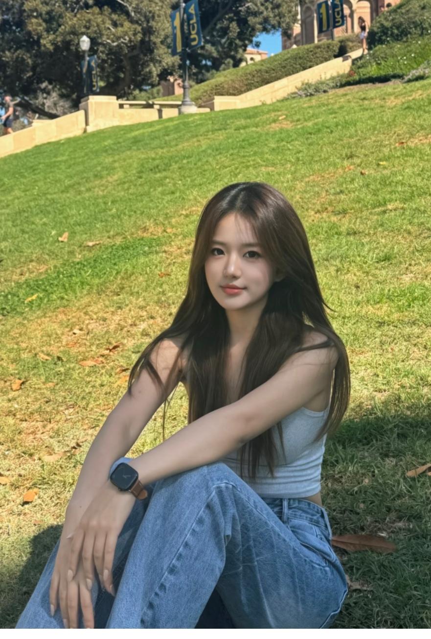 漂亮女孩坐草坪拍照。