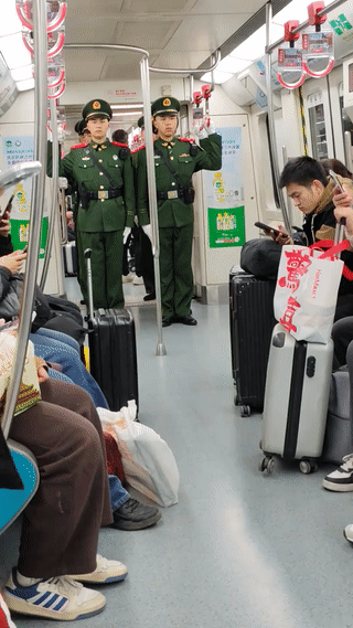 地铁上拍到一队军人乘车。他们都站在地铁车厢正中间的位置扶着扶手乘地铁。尽管中