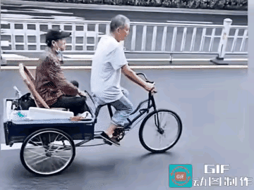 大爷骑着三轮车在快车道上行驶，后面还带着大妈，两个人都挺开心。这不是一天两天了