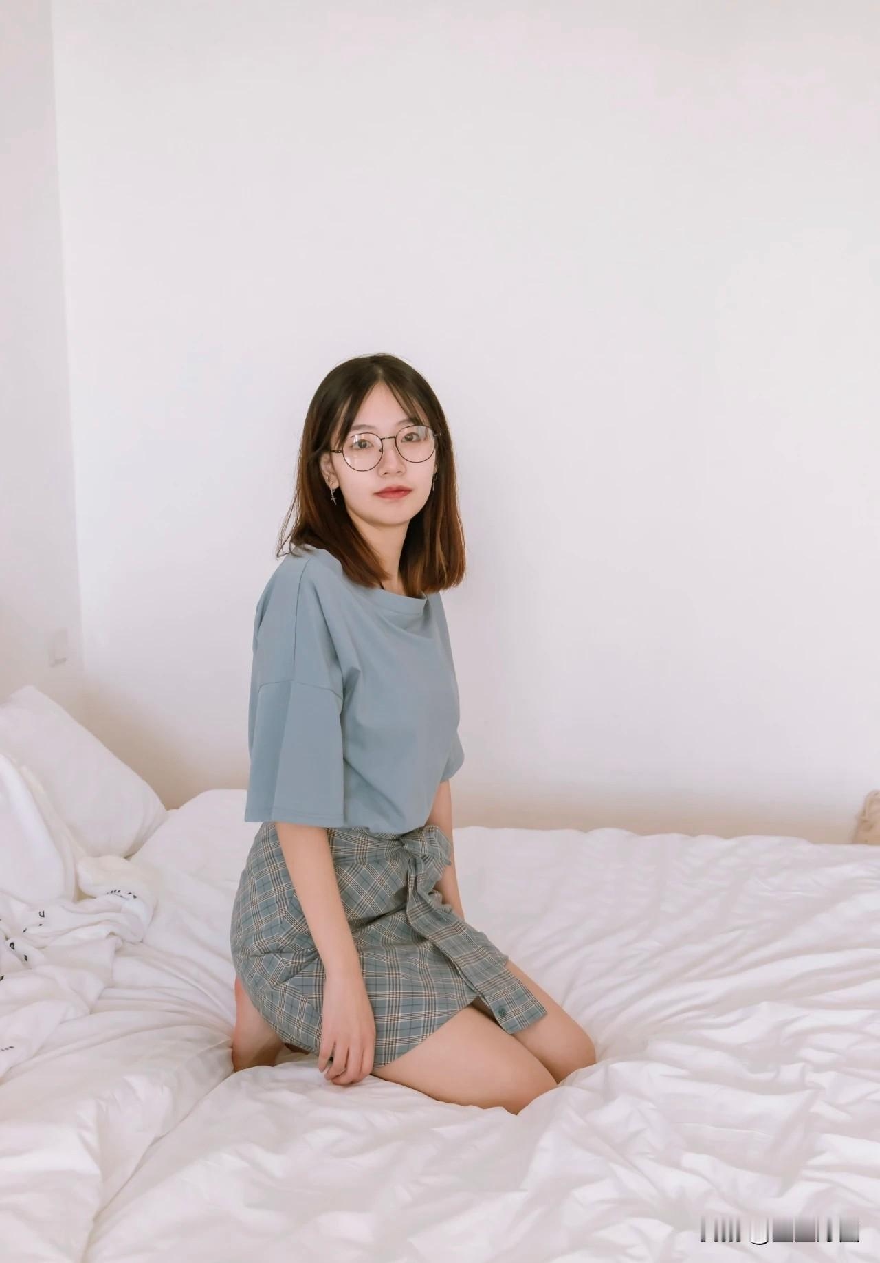 想象一下，妹子坐在温馨的卧室床上，穿着休闲服，阳光透过窗户洒在她身上。她可能正拿
