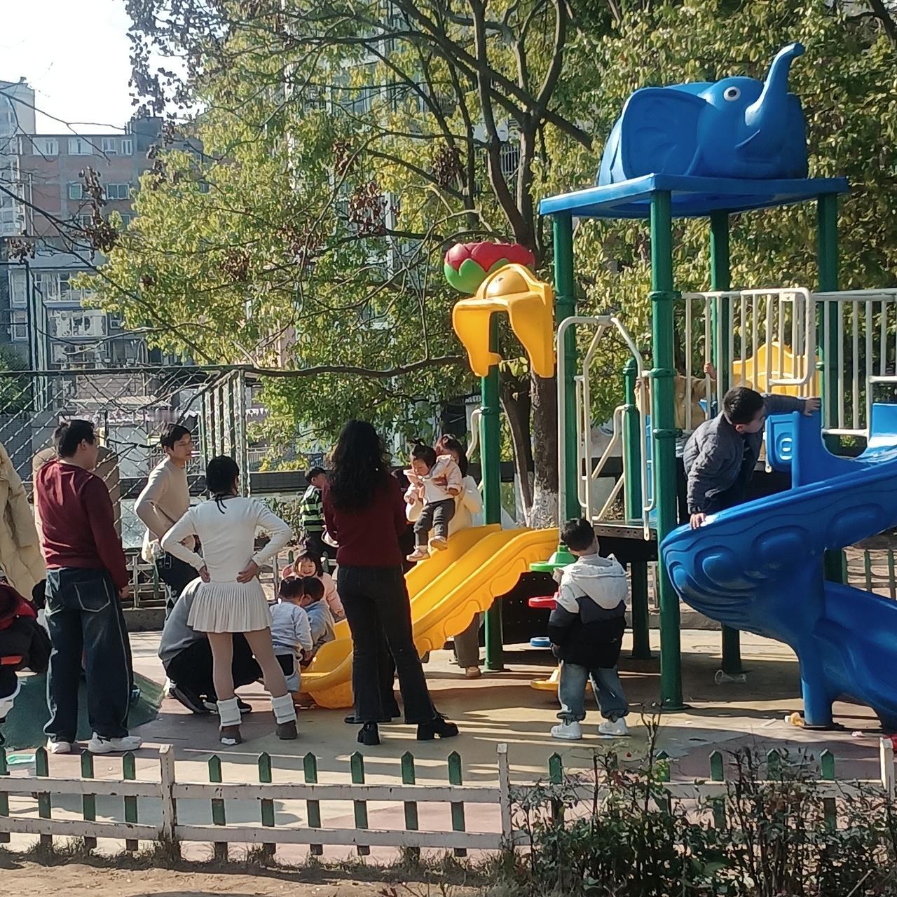 阳光洒满的儿童乐园，孩子们欢快地玩耍，家长在一旁守护。