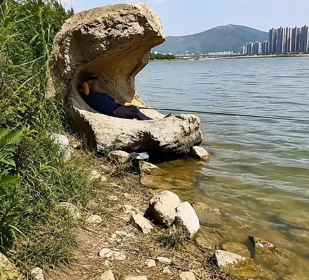 一个人在湖边的岩石上钓鱼。这个位置是不是钓鱼的最佳位置？你有我的位置好吗？有玉没