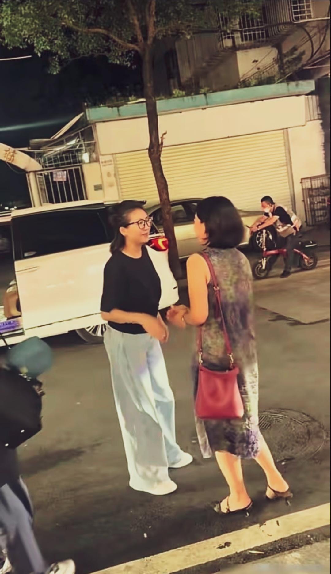王小丫戴着黑框眼镜，一身朴素穿搭，气质知性温和。夜色街边偶遇老友闲谈聊天，神态柔