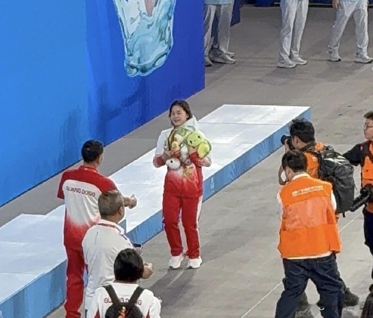 看到全红婵这个下意识的举动吗？收到粉丝的礼物后，兴高采烈的抱着跑到教练何威仪面前