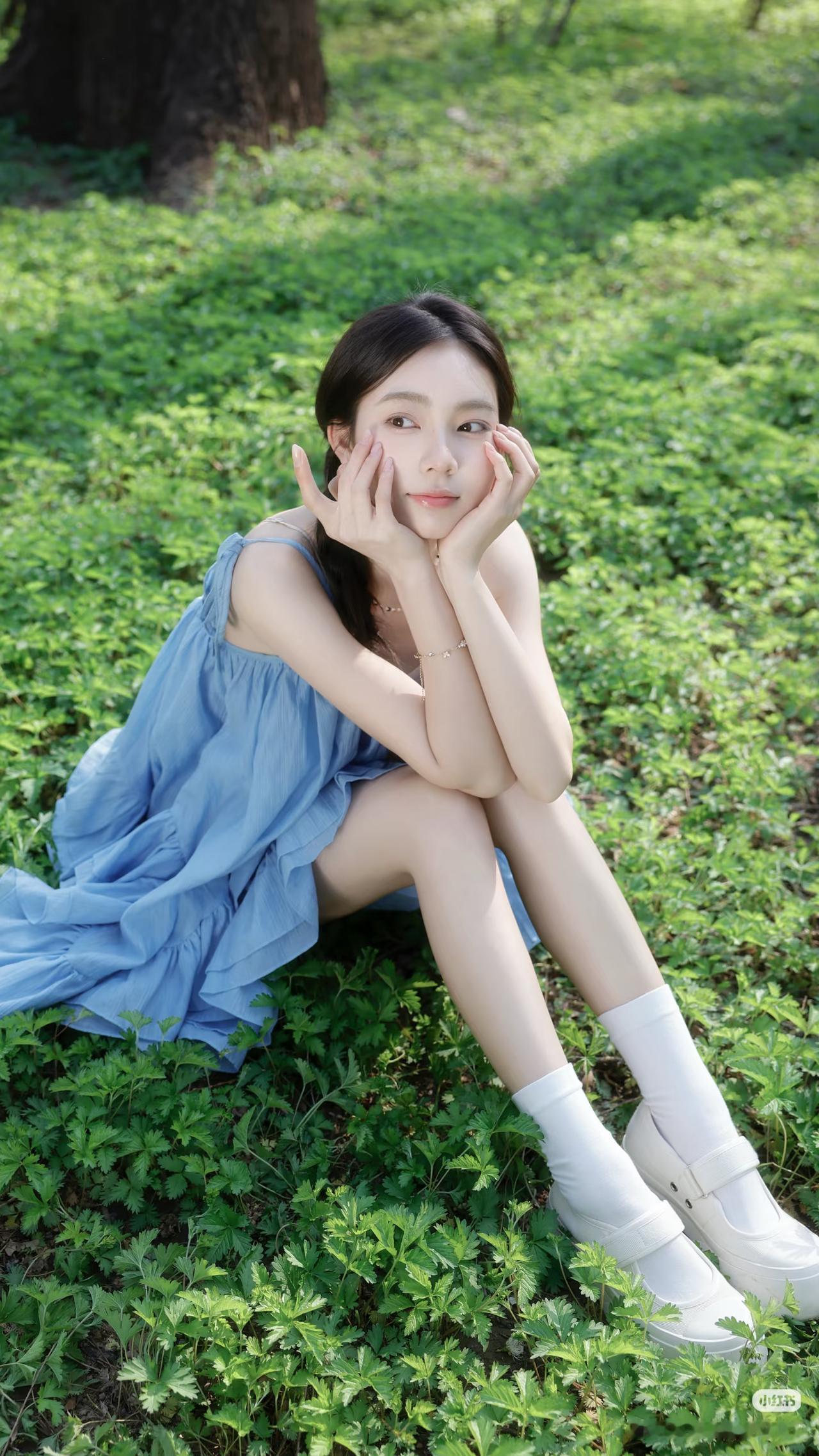 阳光下的蓝裙少女，静坐绿草如茵的公园，清新自然，美不胜收。