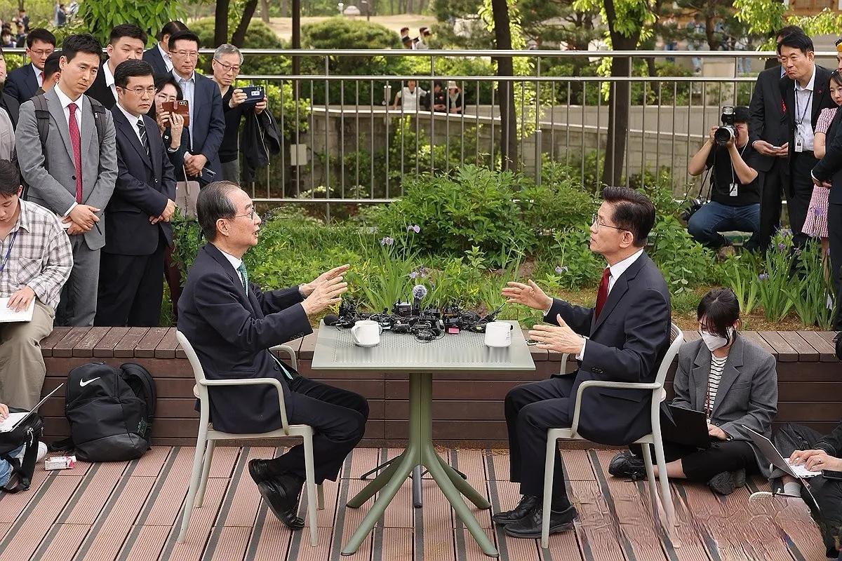 一张咖啡桌上放着几十个传媒的麦和录音设备，一帮媒体围着。两个年过7旬的老江湖