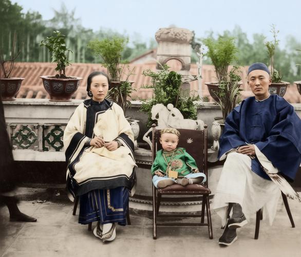 这张照片是晚清时期一张典型的富裕家庭全家福。妻子身着传统的镶边袄裙，头饰精致，面