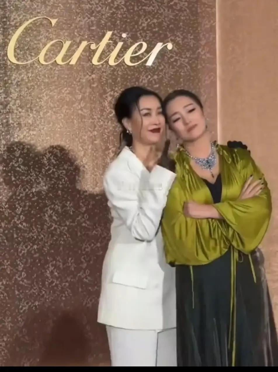 那英碰上巩俐乖多了，不但老实的让巩俐倚靠她身上拍照，还带着甜甜的笑容比手势，那个