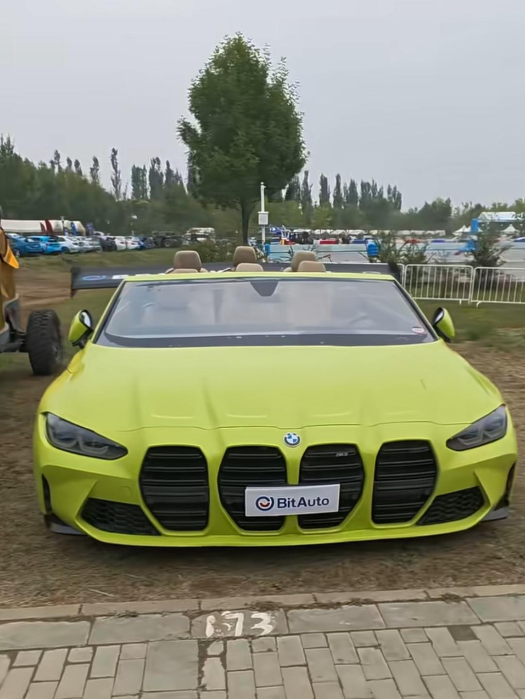 一辆亮黄色的敞篷宝马停在户外。第一次见这么宽的车🚗，你看看能坐多少人？是9座的