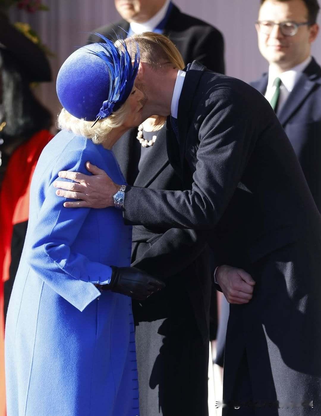 威廉王储亲密的握着卡米拉王后的肩膀，和继母行贴面礼问好！12月3日，查尔斯国王