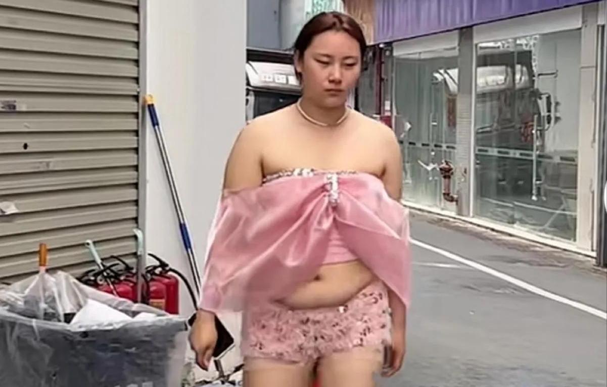 是什么给了她这样的勇气？街边垃圾桶旁，粉色蝴蝶结上衣搭配碎花短裤，微胖身材踩着