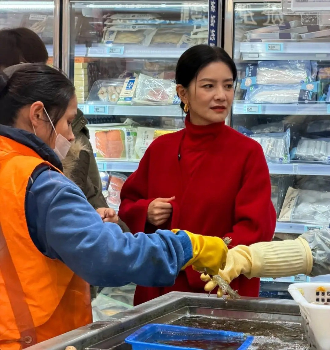 50岁胡可现身超市购买年货被偶遇，她穿着大红色短大衣，挽着发髻，化着精致淡妆。皮