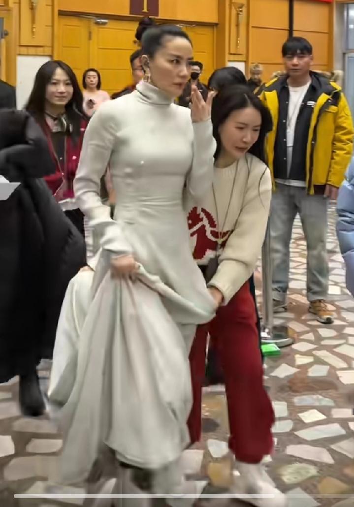 王菲表演结束，从春晚后门离开，阵势很大，工作人员前呼后拥，王菲这一身衣服，大长裙