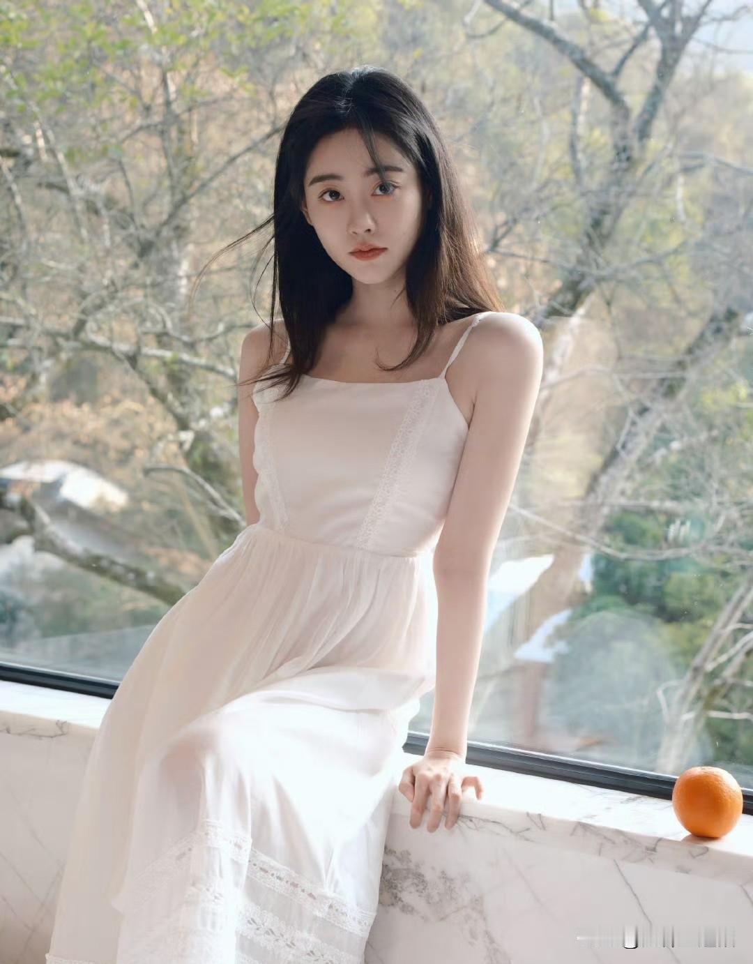 她靠在窗边，穿着白色连衣裙。