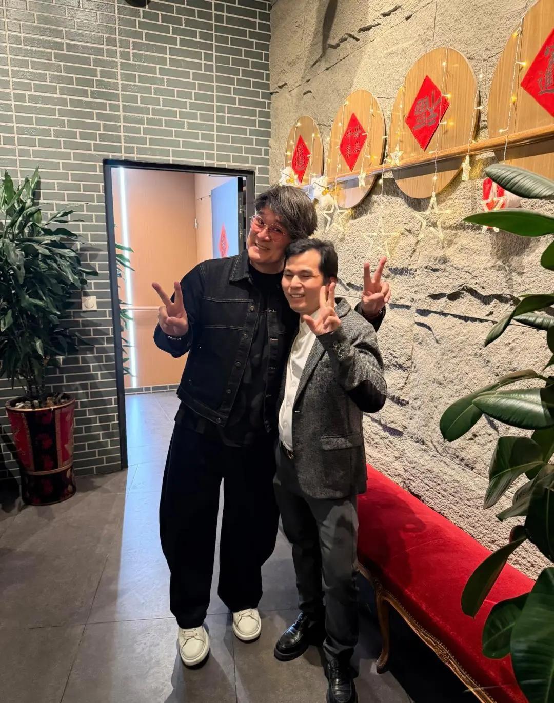 周华健现身法国巴黎餐厅吃饭，在合影时，他和粉丝头和头挨得很近，还比剪刀手，看起来