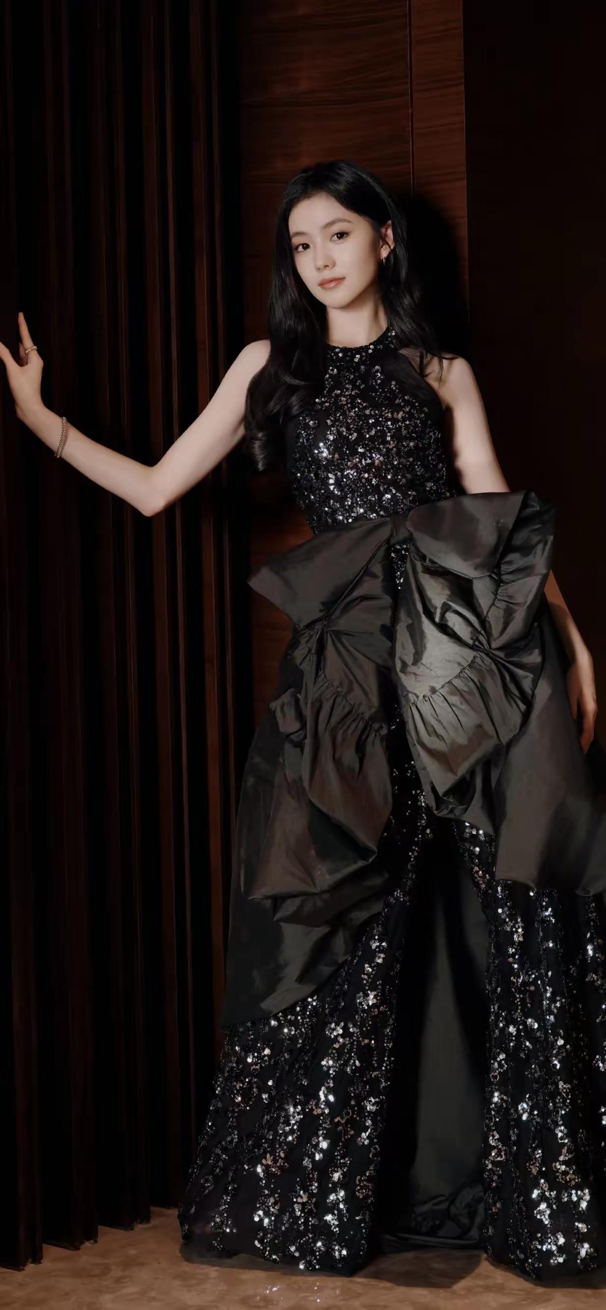 刘浩存，黑裙缀满细碎星光，巨型蝴蝶结勾勒浪漫轮廓，落日与光影交织间，是自带清冷氛