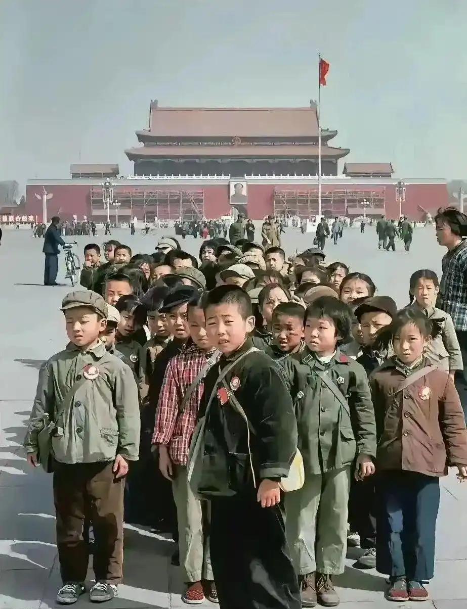 1971年天安门广场上，一群小学生身着简朴的蓝布衣裳，胸前整齐佩戴毛主席像章，稚