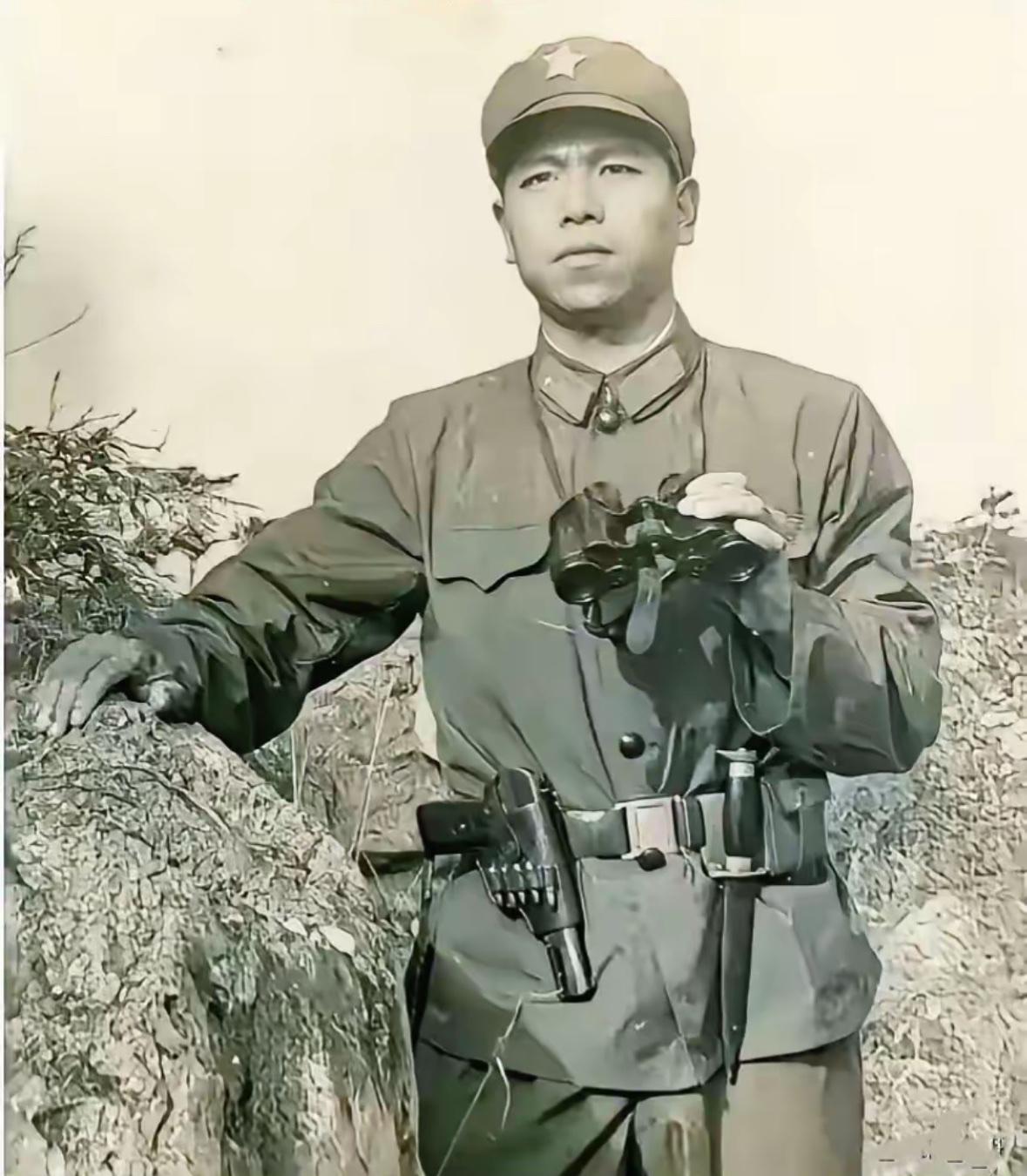 这是崔英顺侦察连长生前照片，他身穿军装，脖子上挂着望远镜，腰上别着手枪，正眉头紧