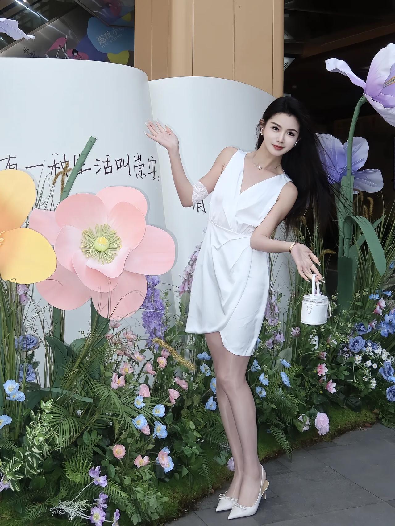 一袭V领无袖白色连衣裙‌，搭配精致小包，整体干净清爽又显气质。