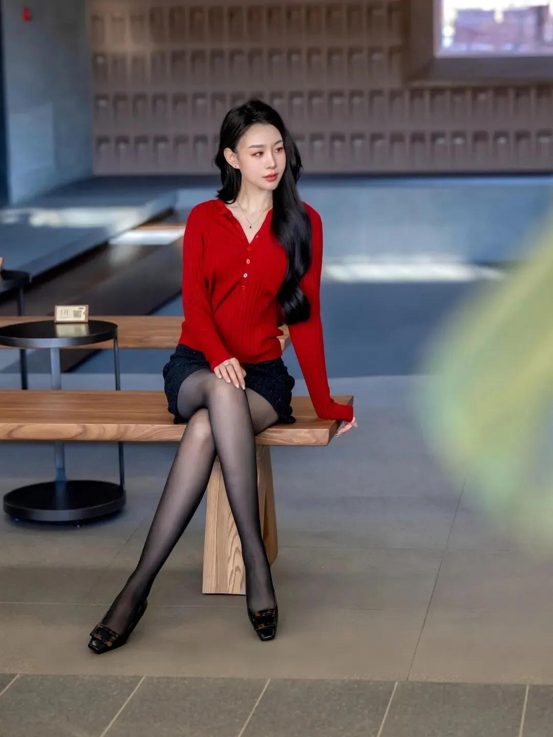 一个穿红衫的姑娘坐在长椅上。