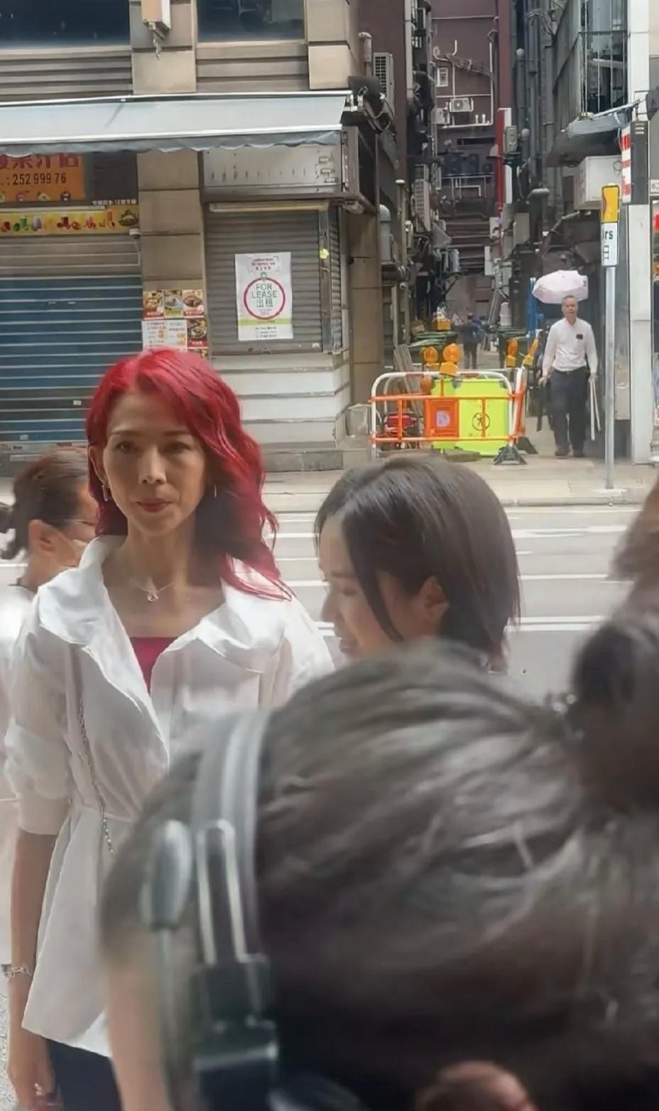 香港街头偶遇蔡少芬拍戏，本人太瘦了人也不年轻。今年52岁的蔡少芬染着一头红色长发